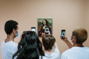 Touristes avec masques anti coronavirus prenant en photo Mona Lisa masquée