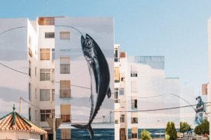Fresque murale sur plusieurs immeubles : pêcheur à la ligne venant de prendre un poisson