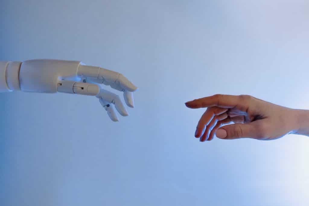 Main d'une intelligence artificielle se tendant vers une main humaine